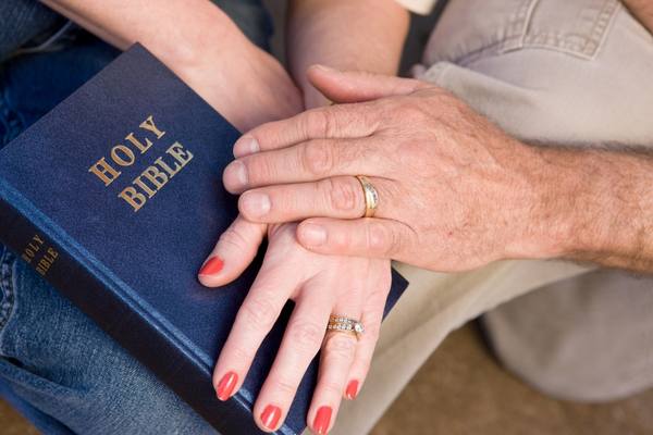 couple holding hands over Bible